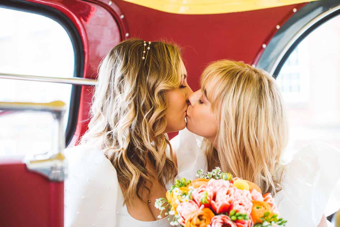 brides kissing on wedding bus
