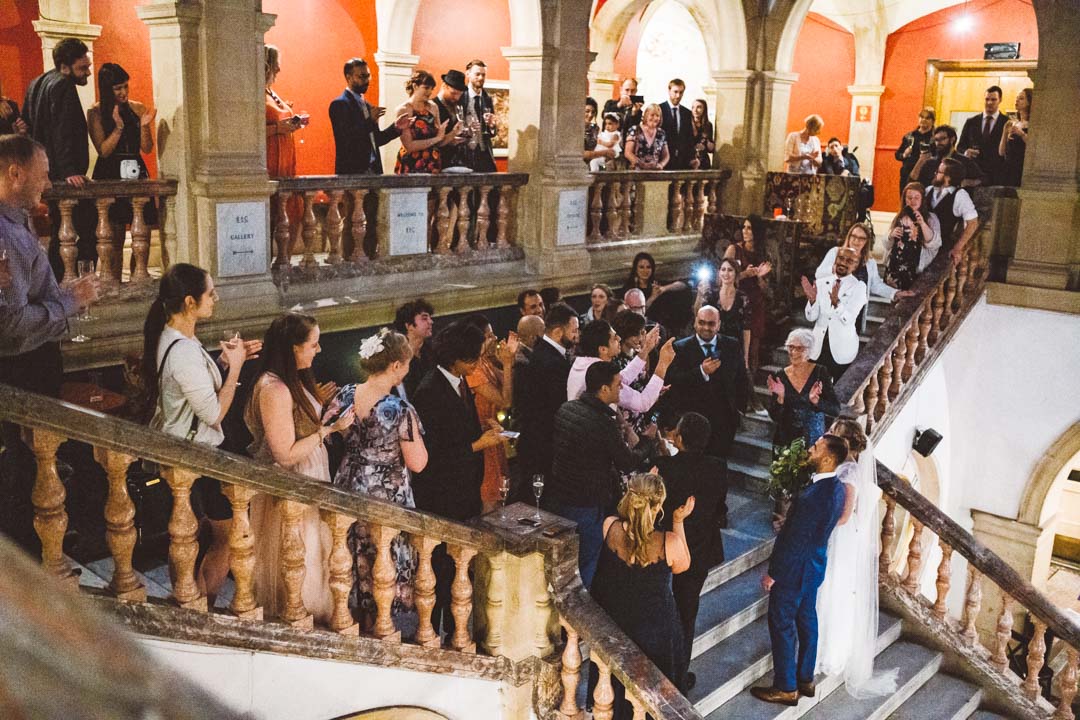 guests welcoming couple on grand stairs
