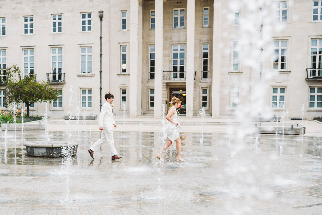 newlyweds running through Fellowship Square fountain